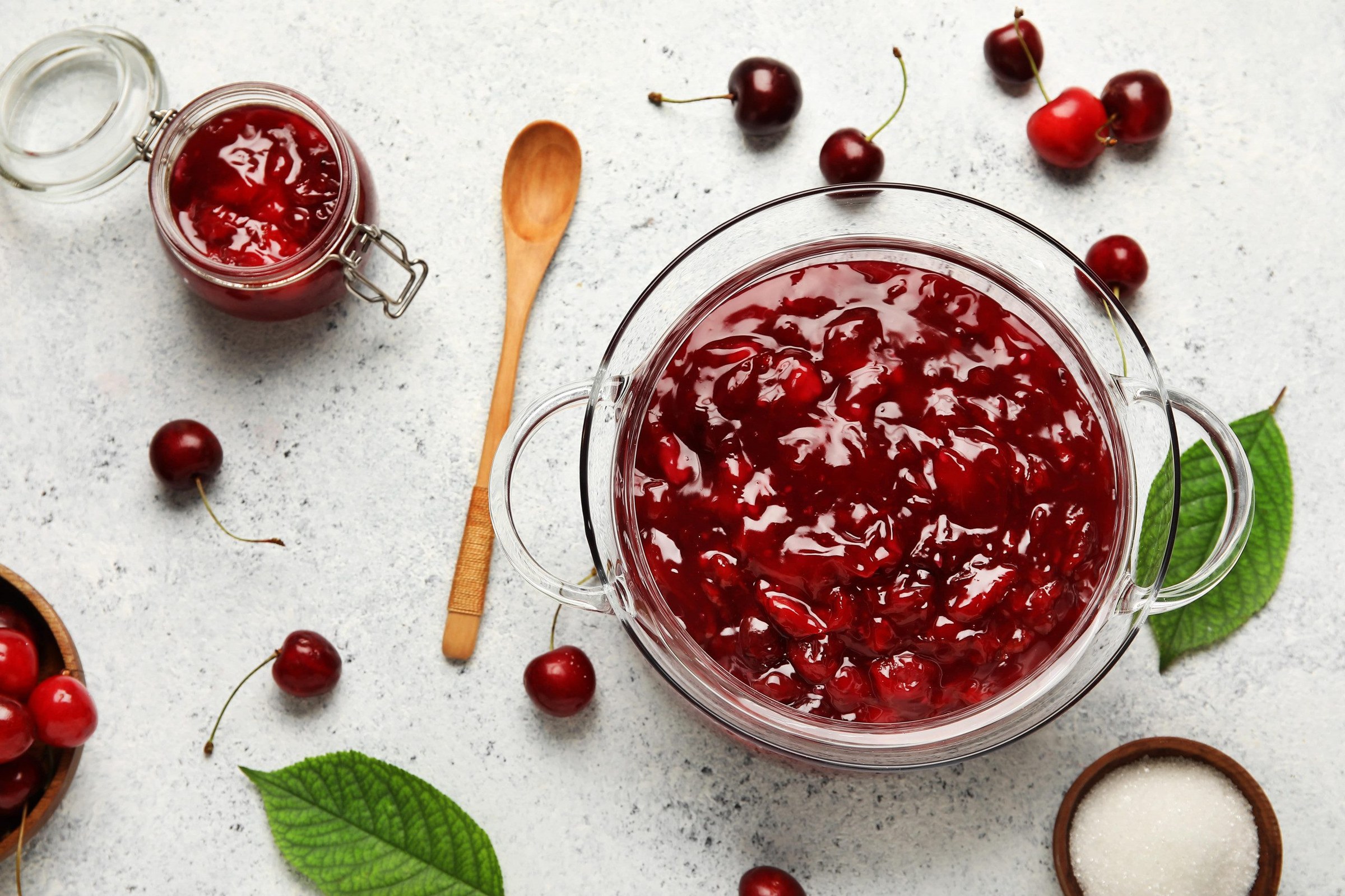 Pots de confiture de cerises maison refroidissant sur un plan de travail