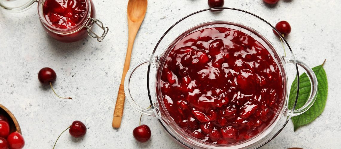 Pots de confiture de cerises maison refroidissant sur un plan de travail